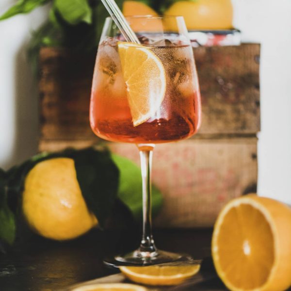 Aperol Spritz cocktail in glass with eco-friendly straw, close-up